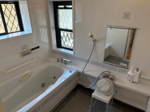 a white bathroom with a tub and a toilet at Anan Seaside House in Anan