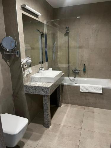 a bathroom with a sink and a toilet and a tub at Park Hotel & Restauracja Browar Brzeg in Brzeg