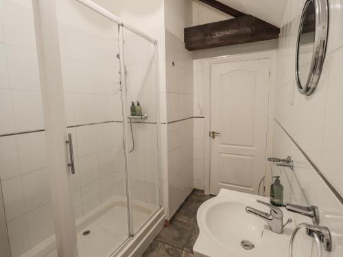 a white bathroom with a shower and a sink at Millers Cottage in Wigton