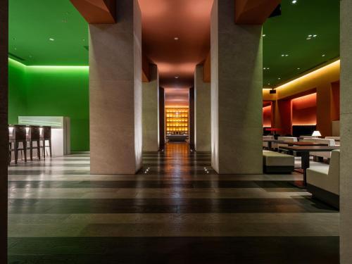 a lobby with columns and green walls and tables at Hotel Il Palazzo in Fukuoka