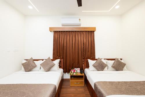 two beds in a room with white walls at FLY VIEW Airport Residency in Nedumbassery