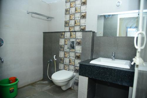 a bathroom with a toilet and a sink and a mirror at Coorg Inn in Kushālnagar