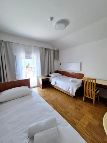 a hotel room with two beds and a chair at Hotel Jelena in Brnaze