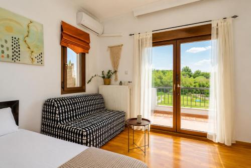 a bedroom with a bed and a chair and a balcony at Suite Acropolis Serres Parking EV Next to Center in Serres