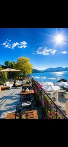 a patio with tables and umbrellas and the water at Resort Antico Verbano in Meina
