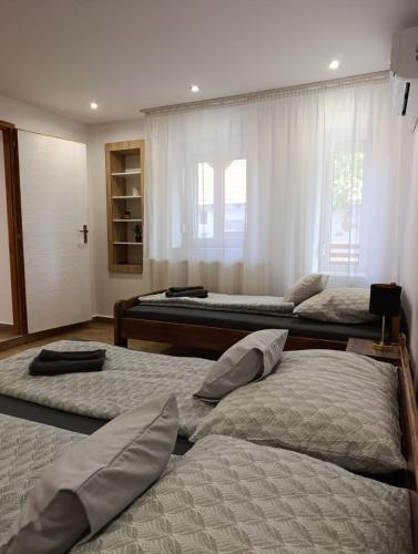 a bedroom with three beds and a window at Oázis Apartman in Sárospatak