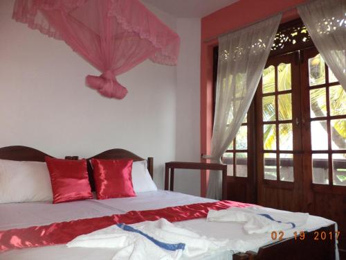 a bedroom with a bed with red and white pillows at Raja174 Homestay in Kandy