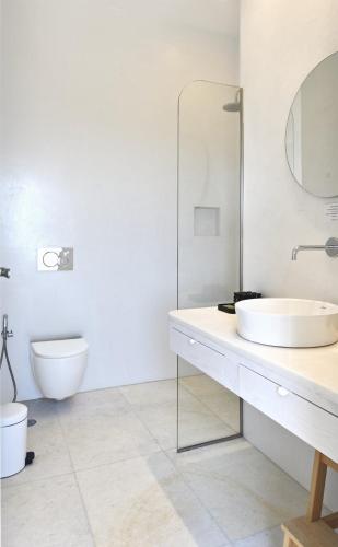 a white bathroom with a sink and a toilet at Theros Apartments 3 in Mylopotas