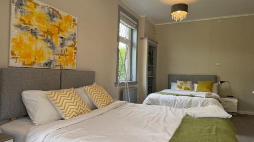 a bedroom with two beds and a painting on the wall at Rose Cottage Edinburgh in Edinburgh