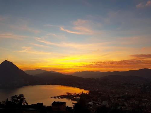 a view of a city and a lake at sunset at Sonniges Paradies mit Seeblick und Panoramaterrasse in Lugano