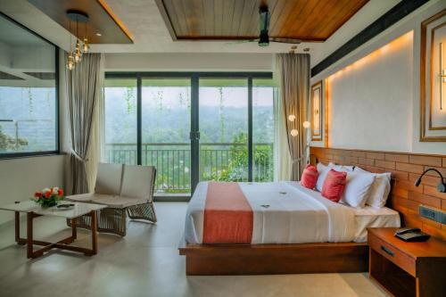 a bedroom with a large bed and a balcony at Mountree Munnar by Kondody Hotels in Anachal