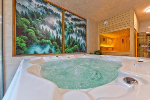 a jacuzzi tub in a bathroom with a painting at Brvnara Mont 3 in Zlatibor