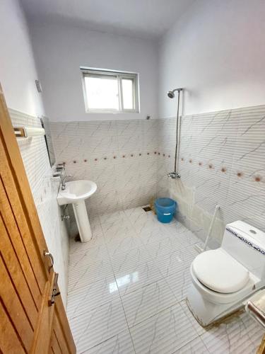 a white bathroom with a toilet and a sink at Lee Rivage Inn in Naran