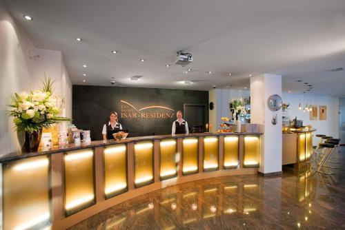 dos mujeres de pie en un bar en un salón en City Hotel Isar-Residenz, en Landshut