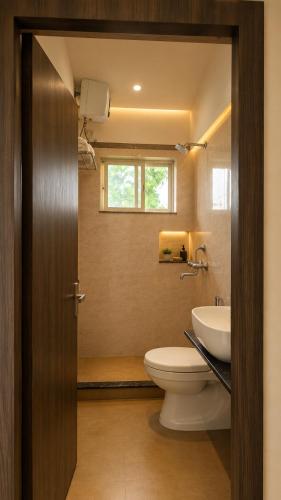 a bathroom with a toilet and a sink and a window at Heritage Garden in Bānsjora