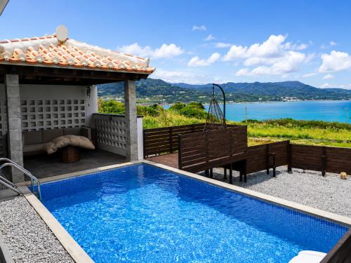 a swimming pool with a table and a view of the water at 風の音 in Motobu