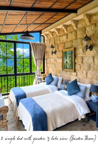 two beds in a room with a stone wall at Laklouk 1808 Lodge by Hansa in ‘Ayn aş Şalīb