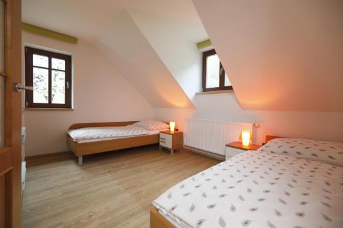 a attic bedroom with two beds and two windows at Na pasekách u lesa apartmán Radost in Osvětimany