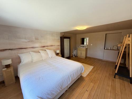 a bedroom with a large white bed and a ladder at gîte du bel étang in Commenailles