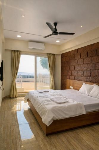 a bedroom with a large bed and a large window at Anandi Hotel Guhagar in Guhagar