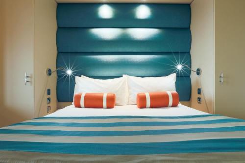 a bed with a blue headboard and two orange pillows at RNLI College in Poole