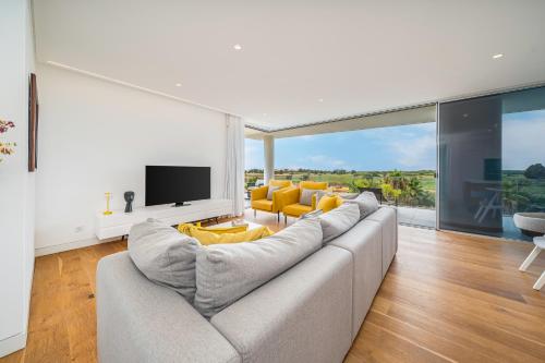 a living room with a large couch and yellow chairs at Vilamoura 4-Bedroom Penthouse with Jacuzzi in Vilamoura