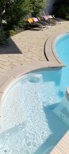 a swimming pool with blue water and a sidewalk at du Côté d'Agnès ! in Ostwald