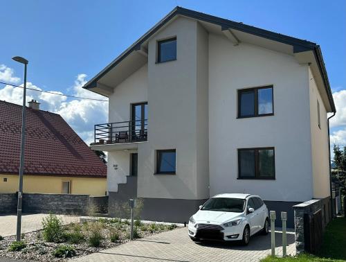 a white car parked in front of a white house at Stylish apartment under the Tatras in Štrba