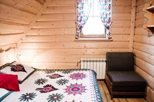 a bedroom with a bed and a chair in a cabin at Domek Regionalny KUBUŚ in Zakopane
