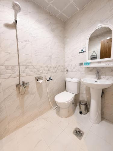 a white bathroom with a toilet and a sink at Luluat Al Badaie Hotel in Mecca