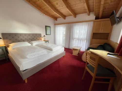a bedroom with a large white bed and a desk at Hotel Stocker in San Valentino alla Muta