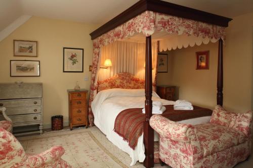 a bedroom with a canopy bed and a chair at Bookers Cottage in Bruern