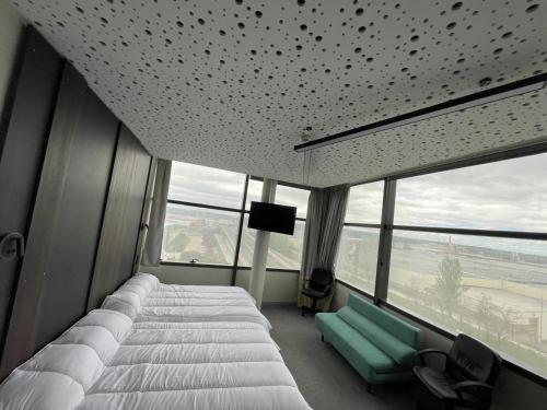 a bedroom with two beds and a couch and windows at Hotel Centro Braseros in Burgos