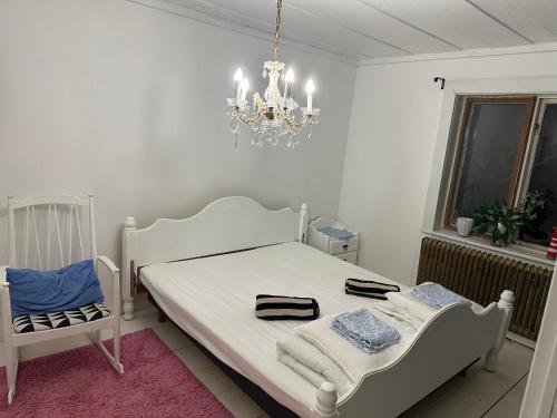 a white bedroom with a bed and a chandelier at Nordic Villa Undrom in Undrom