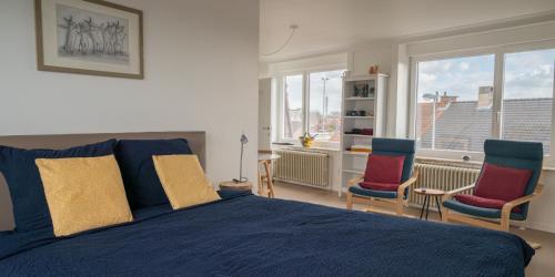 a bedroom with a blue bed and two chairs at Gasthuis 20 verdiep 2 in Kuurne