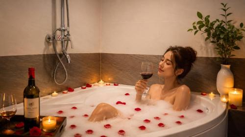 a woman in a bath tub with a glass of wine at Lavender SaPa Hotell & Spa - Free foot soak service in Sapa