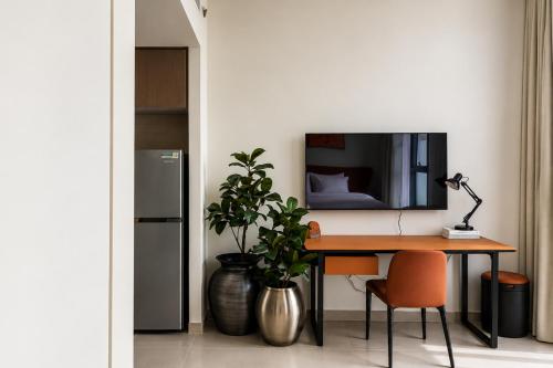 a desk with a plant and a television on a wall at Sahab - Hermes Leather Home in Sharjah