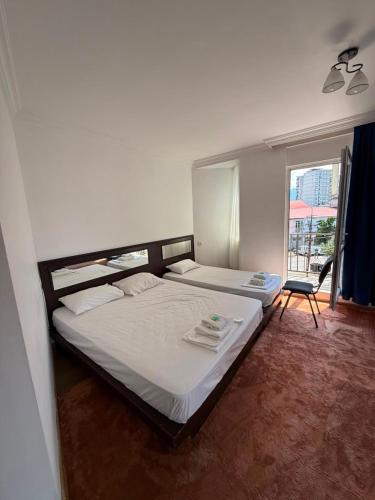 a bedroom with two beds and a chair and a window at Emilia Hotel Batumi Old Town in Batumi
