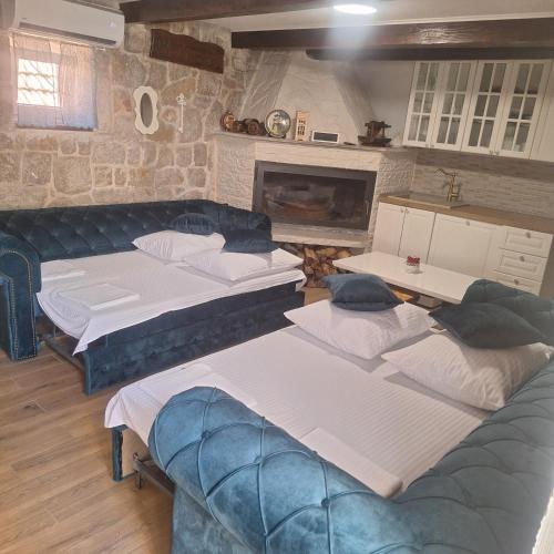 a room with four beds and a couch and a fireplace at Villa Sound of Silence in Poljica Kozička