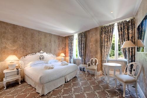 a bedroom with a large white bed and chairs at Hôtel Château de la Tour Cannes in Cannes