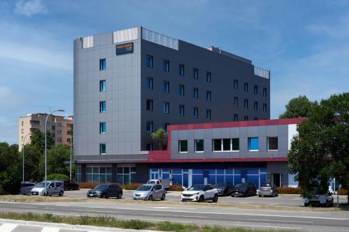 a building with cars parked in a parking lot at Four Points Flex by Sheraton Bologna Airport in Bologna