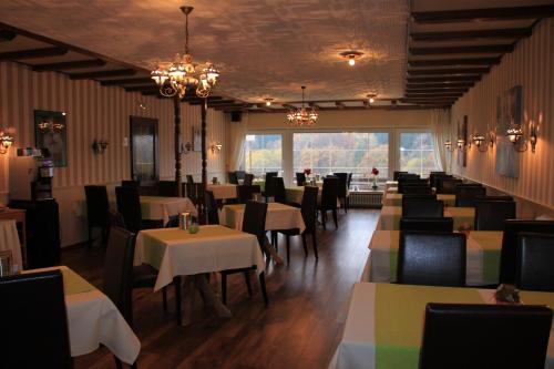 a dining room with tables and chairs and a large window at Eifelhotel Malberg in Malberg