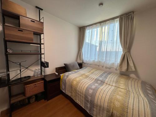a bedroom with a bed and a window at 白樺ハウス女性&家族専用 送迎あり小型犬可 in Chigasaki