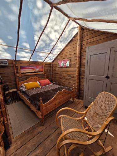 a bedroom in a wooden cabin with a bed and chairs at Destination Ailleurs eco-domaine & spa in Castellane