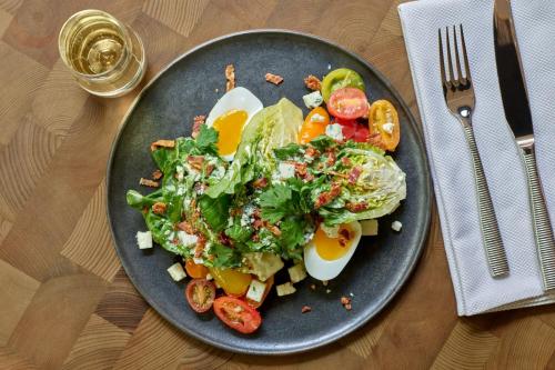 a plate of food with eggs and salad on a table at Hotel Clio, a Luxury Collection Hotel, Denver Cherry Creek in Denver