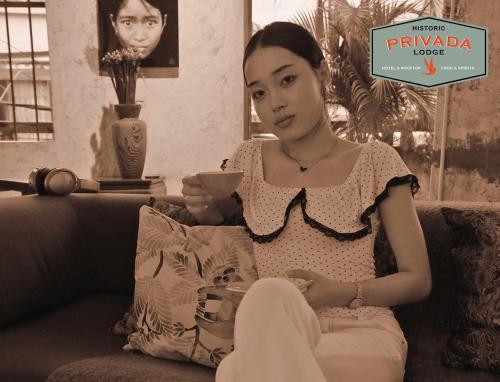 a woman sitting on a couch with a sign that reads pyrimida more at Privada Lodge - Historic Hotel in Kratie