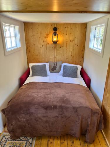 a large bed in a room with wooden walls at Schlosswirts Wohnmobilstellplatz, Schäferwagen und Bauwagen Großglockner Hochalpenstrasse in Döllach