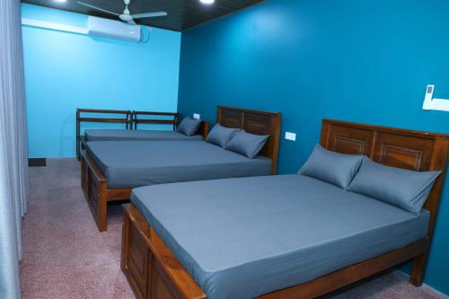two beds in a room with blue walls at Oasis Guest House in Jaffna