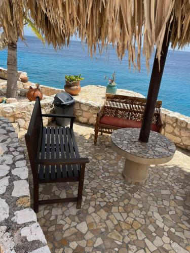 two benches and a table in front of the ocean at Lagun Paradise Curacao in Willemstad