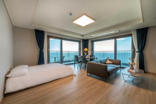 a bedroom with a bed and a couch and a table at More than Sokcho in Sokcho